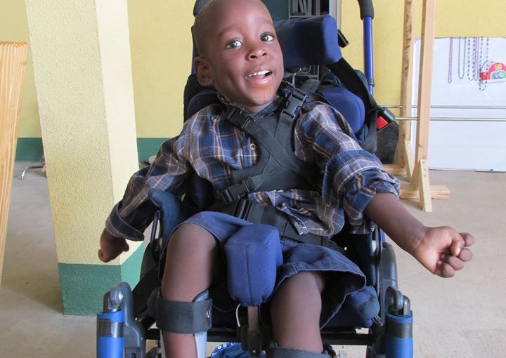 Smiling child seated in adaptive wheelchair indoors