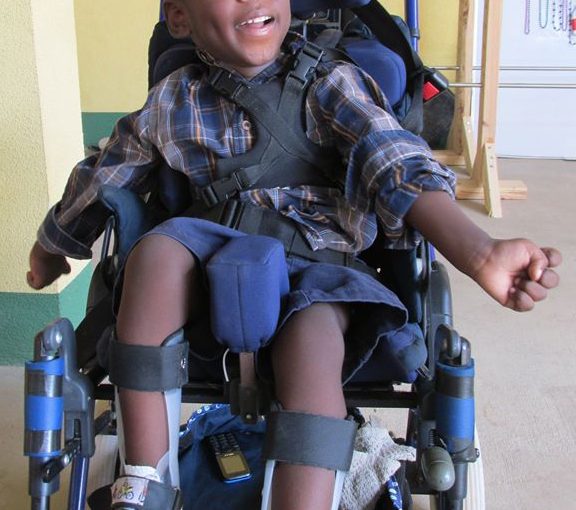 Smiling child in wheelchair wearing plaid shirt