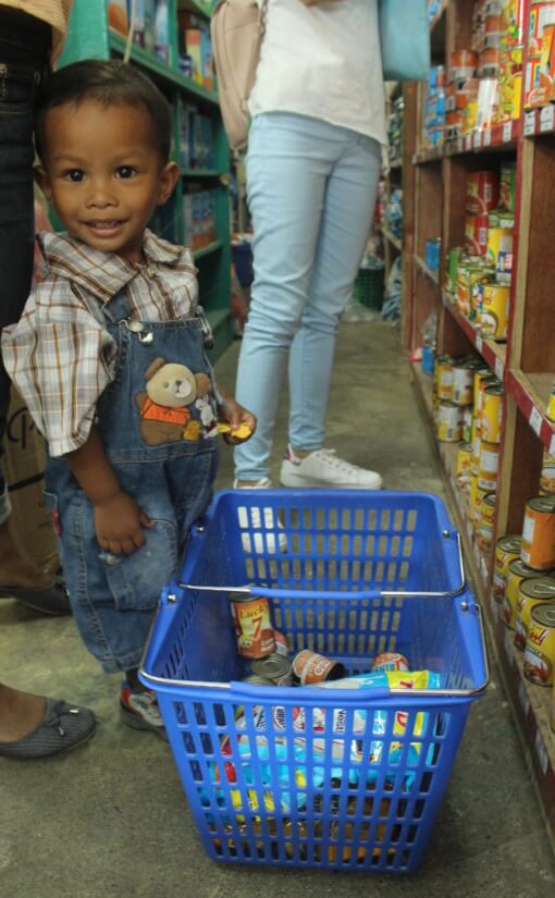Smiling toddler in grocery aisle with basket