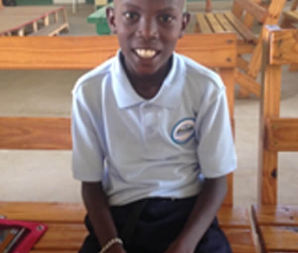 Smiling schoolboy sitting on wooden bench
